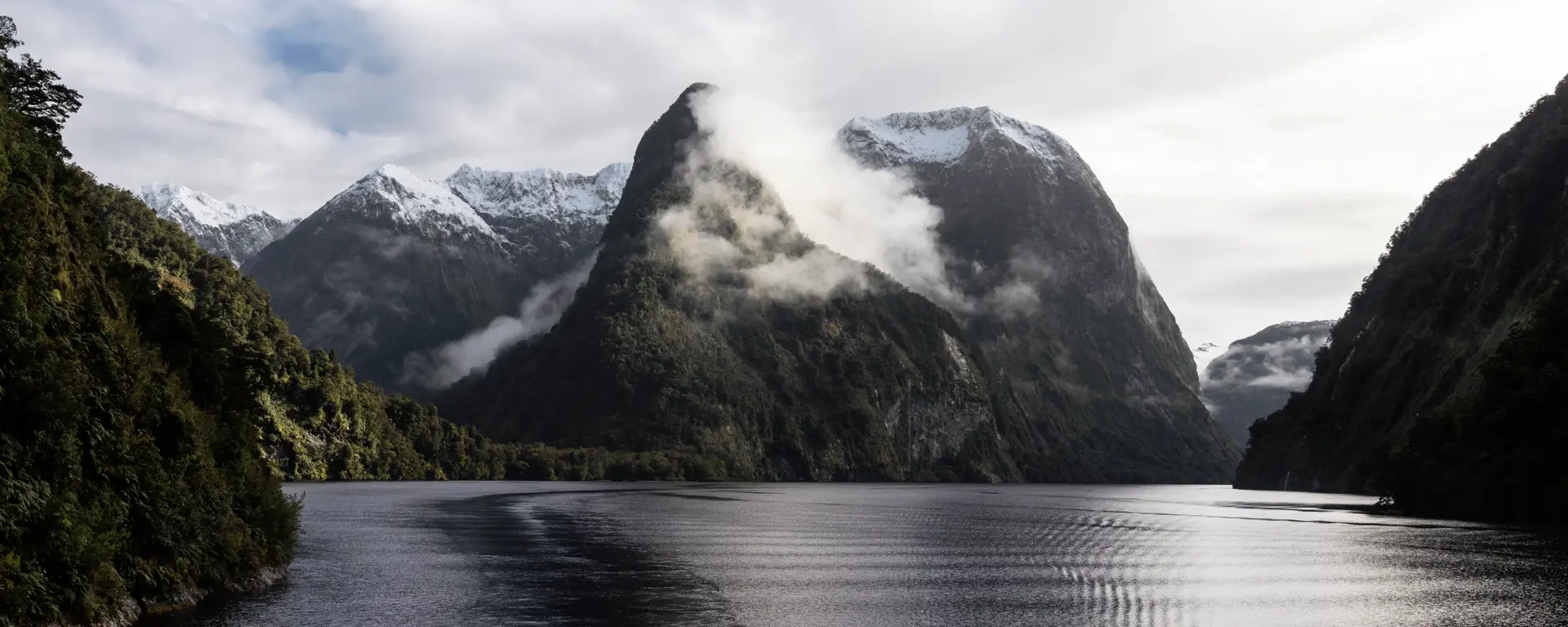 Misty mountains rising above the calm waters of Doubtful Sound.