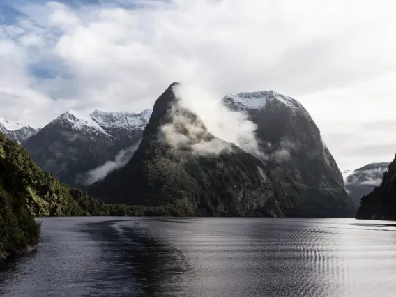 Misty mountains rising above the calm waters of Doubtful Sound.