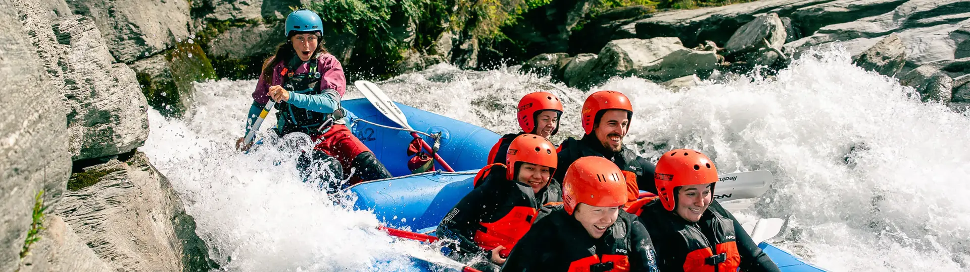 Group white-water rafting through rocky rapids near Queenstown.