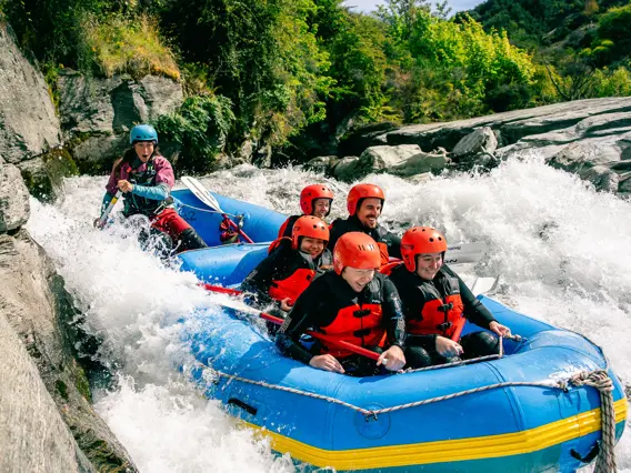 Group white-water rafting through rocky rapids near Queenstown.