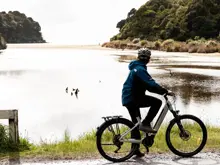 Guest riding an e-bike beside a scenic Stewart Island bay.
