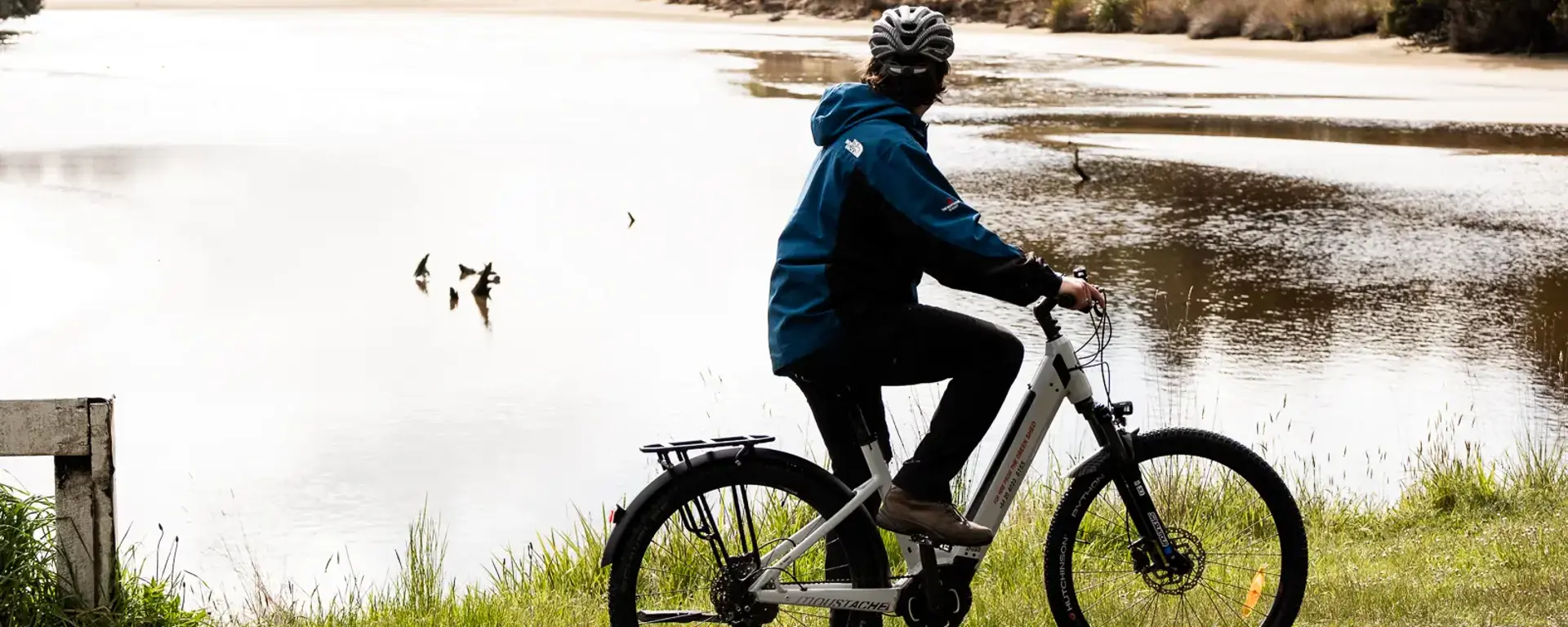 Guest riding an e-bike beside a scenic Stewart Island bay.