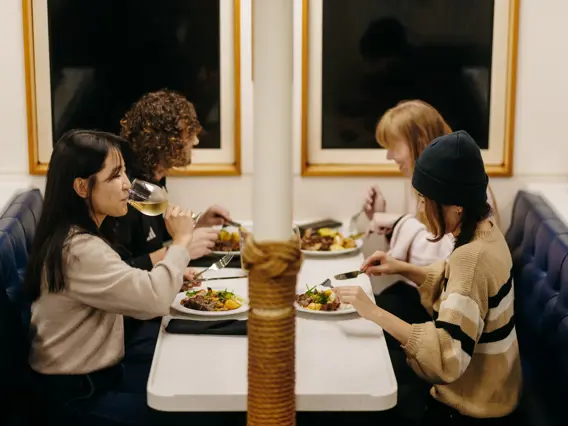 Guests sharing a meal inside a Milford Sound cruise vessel.