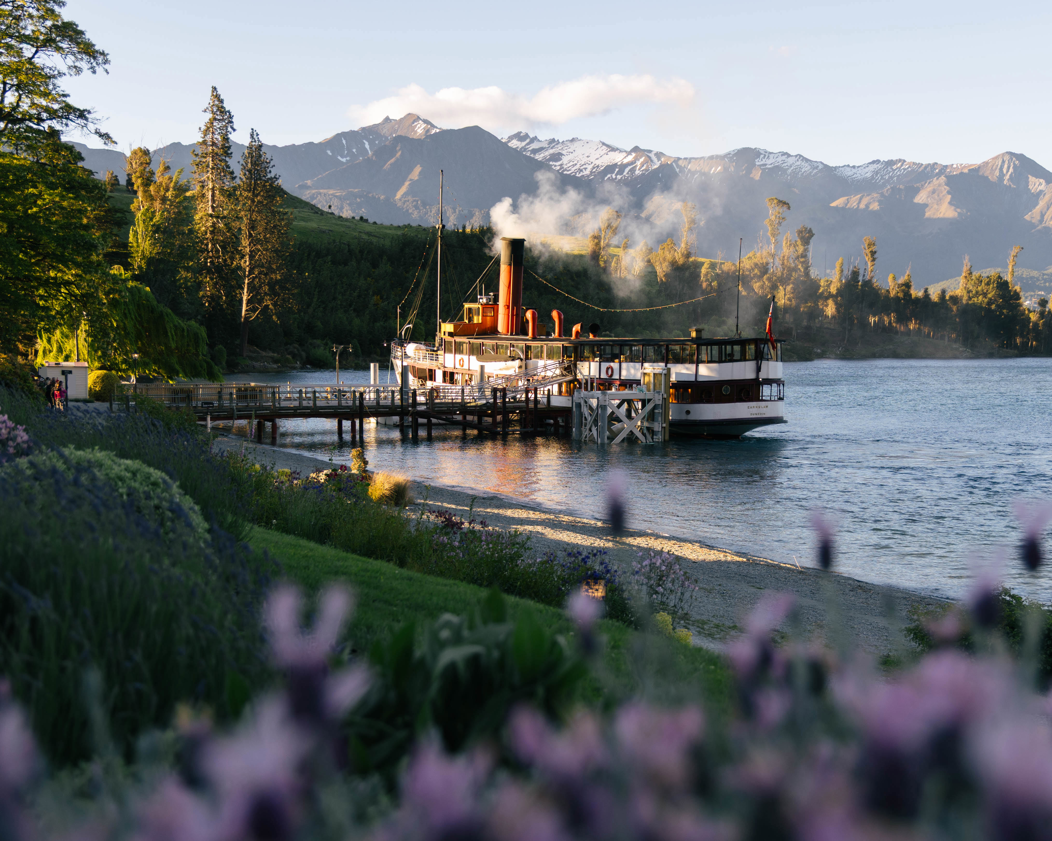 The TSS Earnslaw steamship docked lakeside at Walter Peak with beautiful gardens. 