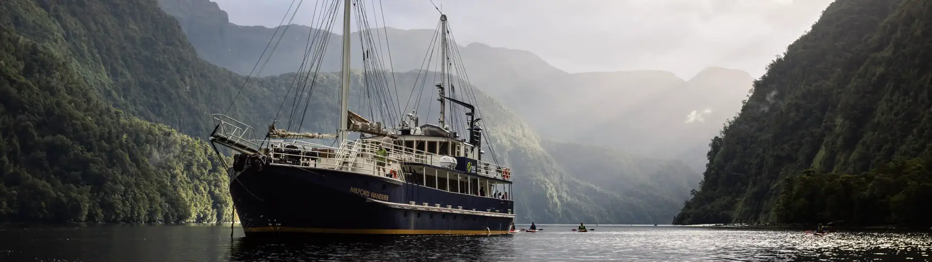 Expedition vessel cruising through a dramatic mountain fiord.