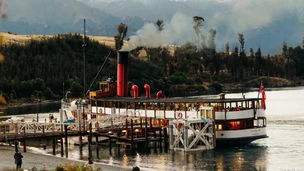 TSS Earnslaw steamship docked against a mountain backdrop.