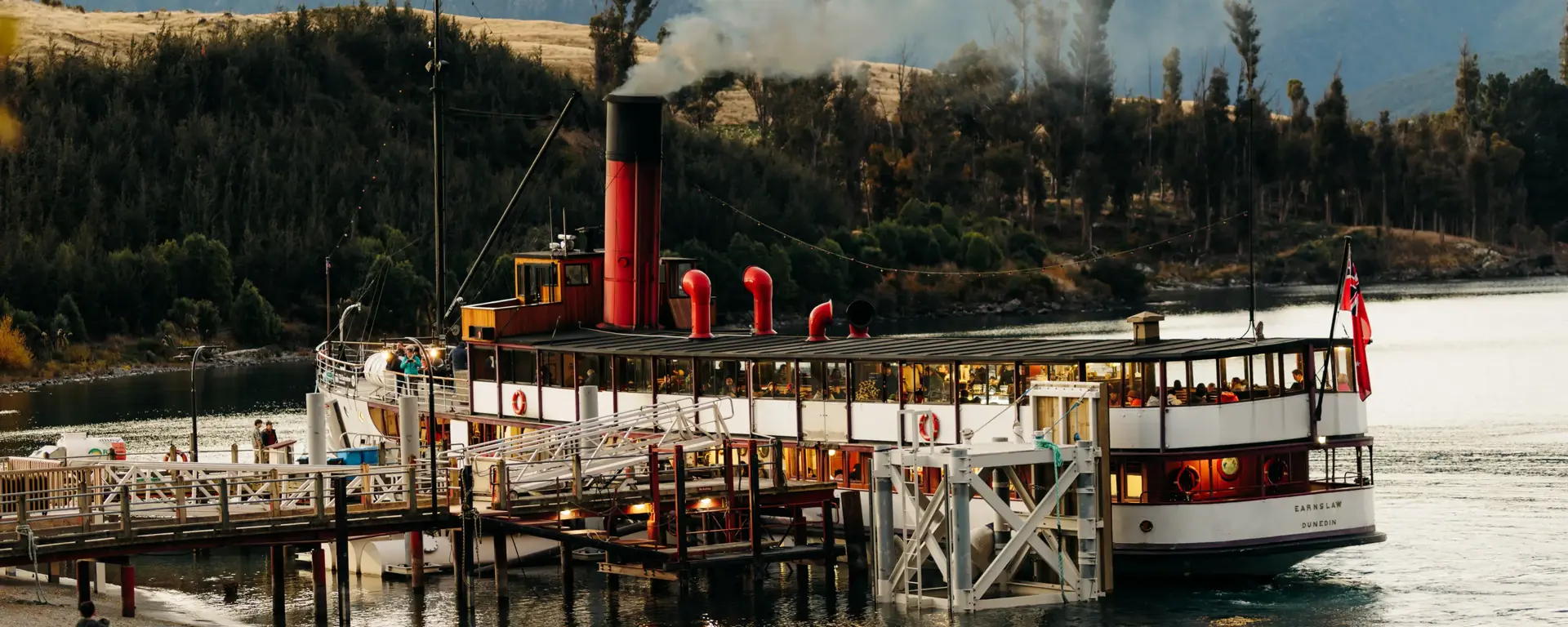 TSS Earnslaw steamship docked against a mountain backdrop.