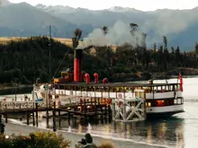 TSS Earnslaw steamship docked against a mountain backdrop.