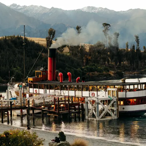 TSS Earnslaw steamship docked against a mountain backdrop.