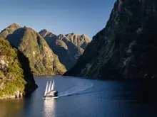 Cruise vessel sailing through the dramatic mountains of Doubtful Sound.