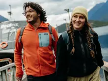 Two friends smiling together on the deck of a Doubtful Sound cruise.