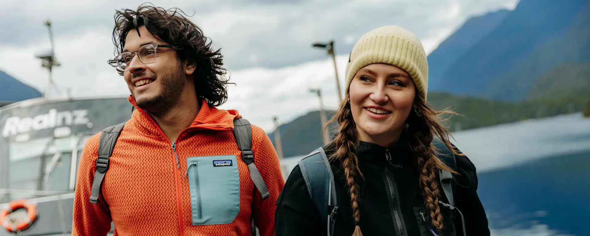 Two friends smiling together on the deck of a Doubtful Sound cruise.