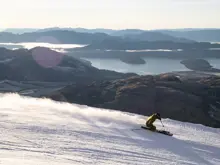 Skier carving down Treble Cone with mountain and lake views.