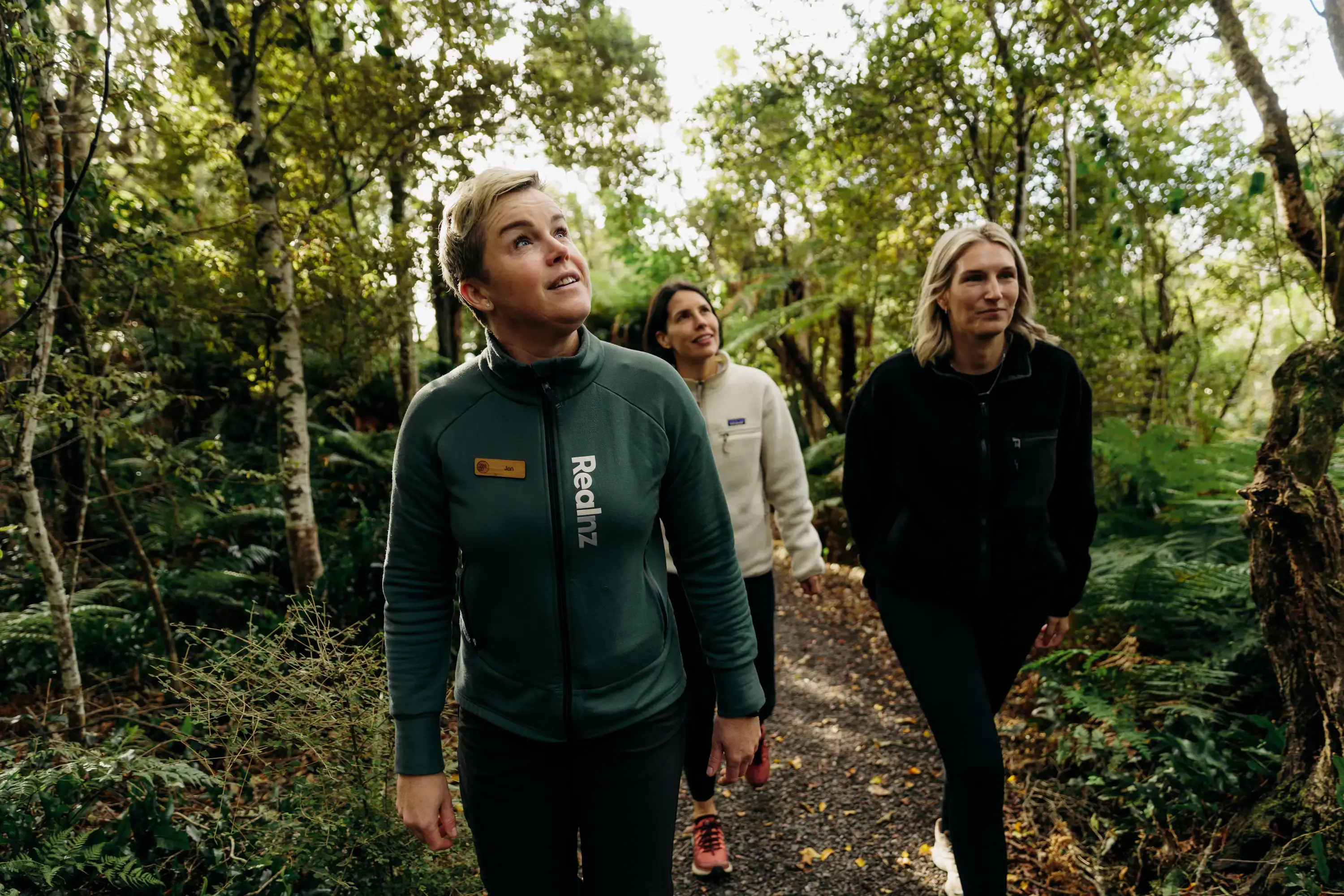 Three people walking through dense native forest on Oneke Island.