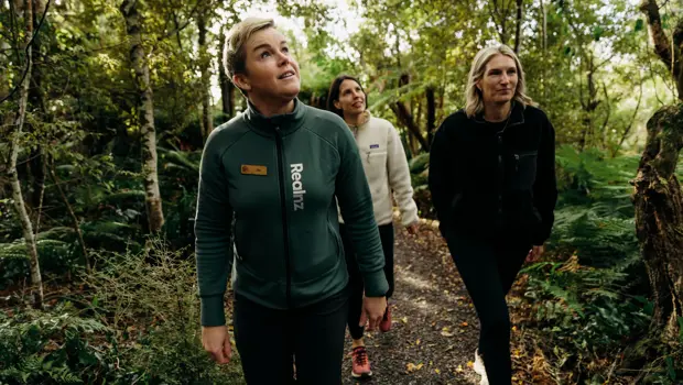 Three people walking through dense native forest on Oneke Island.