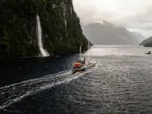 Expedition vessel cruising past a waterfall in Dusky Sound.