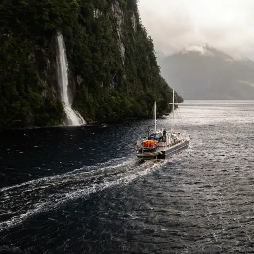 Expedition vessel cruising past a waterfall in Dusky Sound.