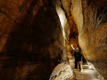 Visitor walking through a narrow rock passage inside the Te Anau Glowworm Caves.
