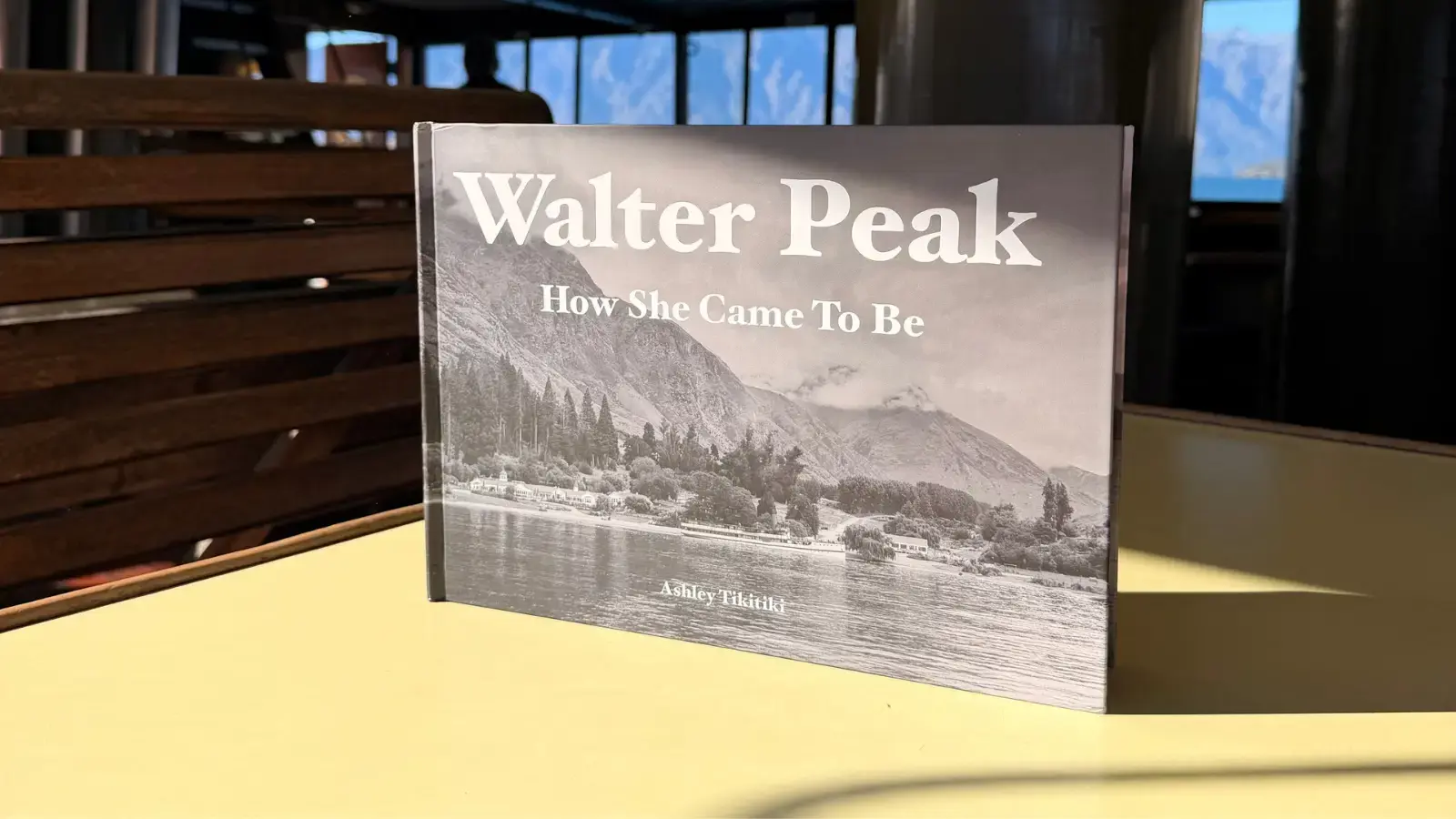 A book titled Walter Peak How She Came To Be sits on a table on a cruise boat. 
