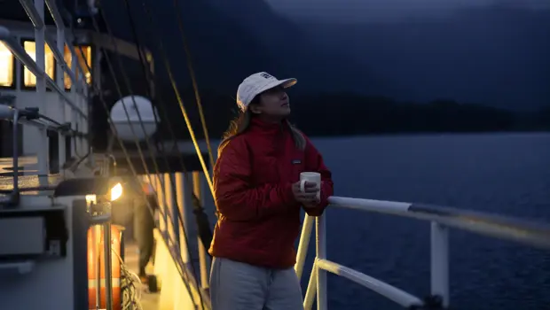 Woman holding a warm drink on a boat during an overnight cruise.