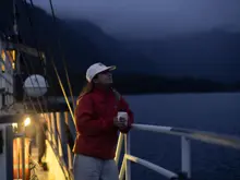 Woman holding a warm drink on a boat during an overnight cruise.