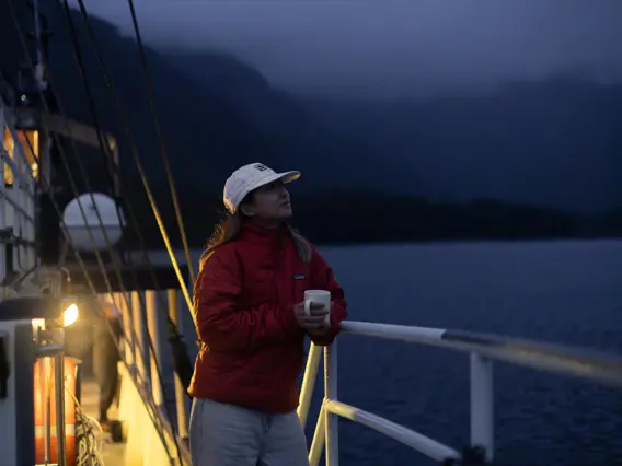 Woman holding a warm drink on a boat during an overnight cruise.