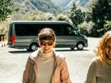Cruise guest outdoors beside a coach in Milford Sound.