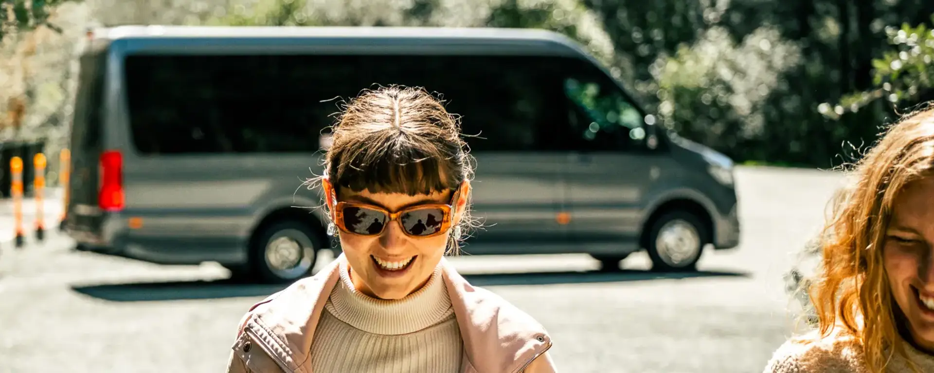 Cruise guest outdoors beside a coach in Milford Sound.