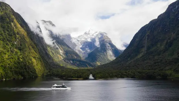 Cruise vessel sailing through the mountains of Milford Sound.