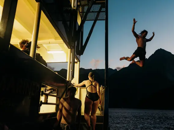Guest jumping from a cruise vessel at sunset.