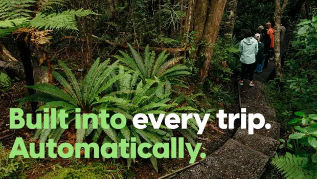 People walking through native forest with text: “Built into every trip. Automatically.”