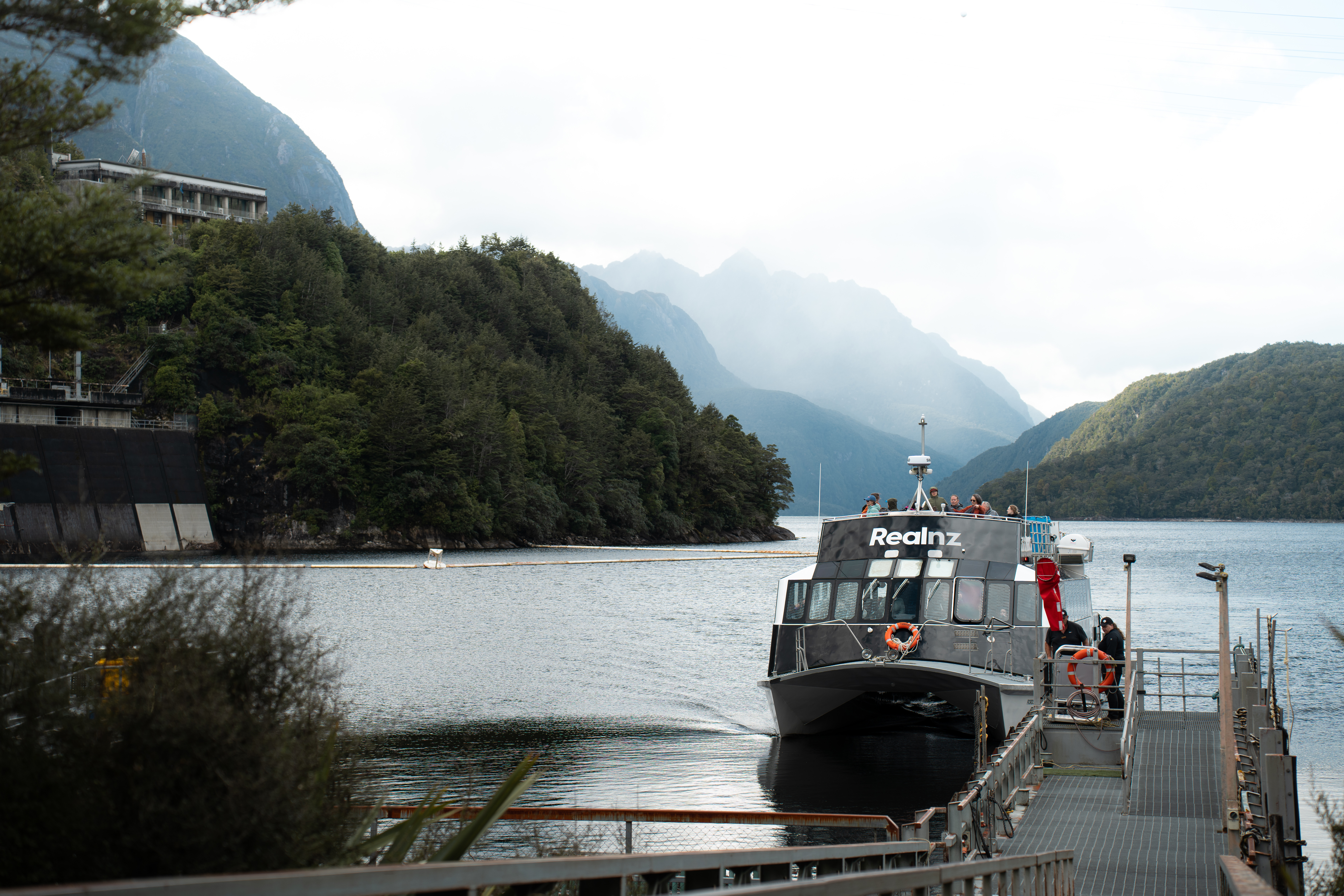 A RealNZ branded boat docks at a wharf on Lake Manapouri on it's way to Doubtful Sound.