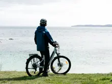 Guest with an e-bike enjoying coastal views on Stewart Island.