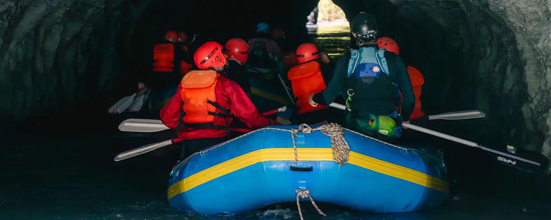 A group of rafters enter the opening of a cave tunnel.
