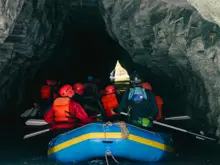 A group of rafters enter the opening of a cave tunnel.