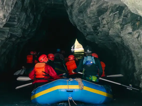 A group of rafters enter the opening of a cave tunnel.