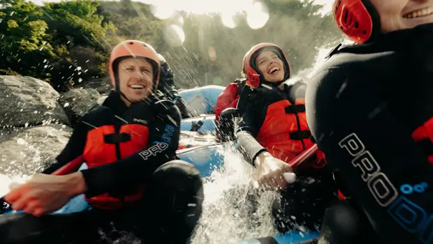 Rafters laughing as they navigate splashing white-water rapids.