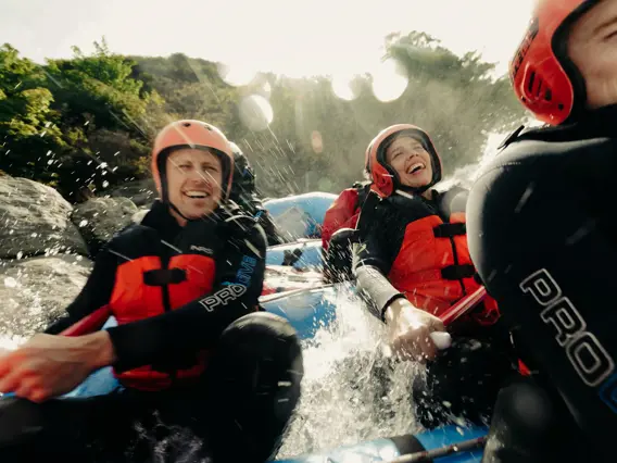 Rafters laughing as they navigate splashing white-water rapids.