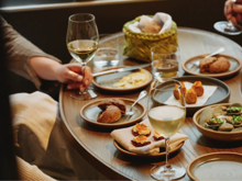 A cozy table setting with small plates of gourmet food and glasses of white wine.