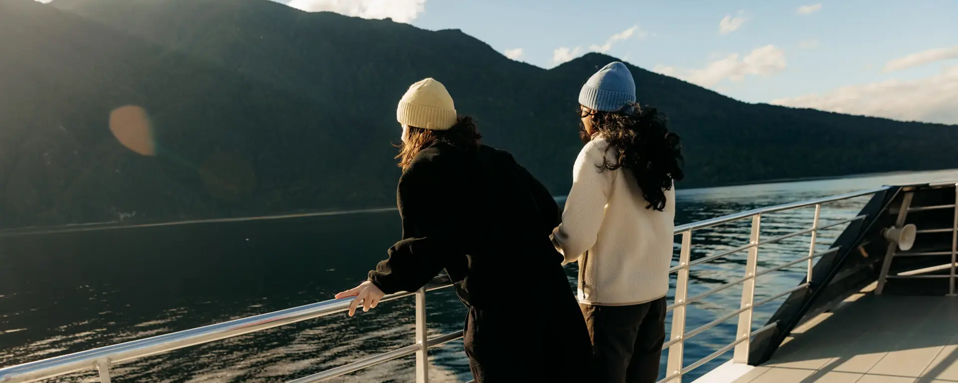 Two guests enjoying mountain and lake views from a cruise boat near Te Anau.