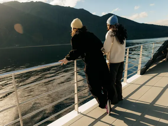 Two guests enjoying mountain and lake views from a cruise boat near Te Anau.