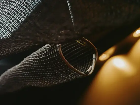 Close-up of a woven mesh decoration or netting, softly lit in a warm-toned interior.