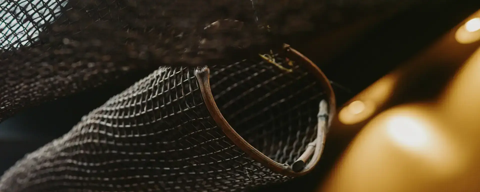 Close-up of a woven mesh decoration or netting, softly lit in a warm-toned interior.