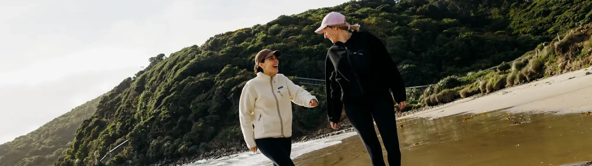 Two people walking along a sandy beach on Rakiura Stewart Island.