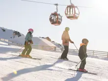 Family skiing together beneath the chairlift at Cardrona Alpine Resort.