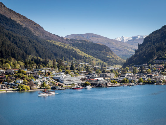 Drone view of the centre of Queenstown lakefront with with the famous TSS Earnslaw cruising on the lake and snow-capped mountains in the background.