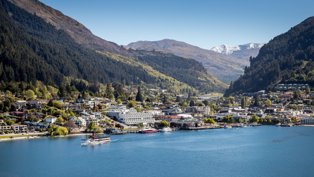 Drone view of the centre of Queenstown lakefront with with the famous TSS Earnslaw cruising on the lake and snow-capped mountains in the background.