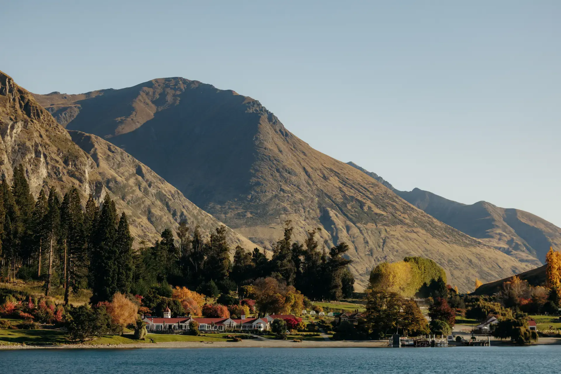 View from the lake of Walter Peak High Country Farm on a bluebird day, with the mountains towering behind. 